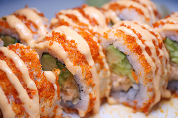 Colorful sushi rolls topped with spicy sauce and crispy bits