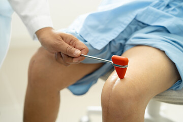Asian doctor physiotherapist examining, massaging and treatment knee and leg of senior patient in orthopedist medical clinic nurse hospital.
