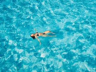 Woman swimming in clear blue sea on sunny day. Drone view