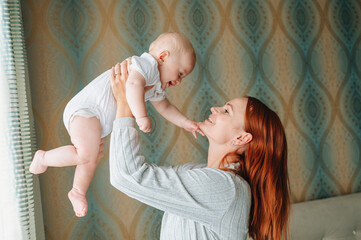 A happy mother holds a cheerful baby in her arms