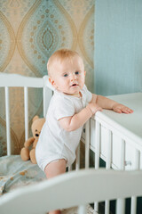 Portrait of a 8 month old crawling baby on the bed. the baby smiles and looks at the camera