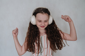 A carefree girl with headphones listens to music and dances