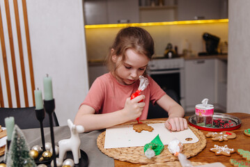 Happy funny little girl bake christmas cookies on cozy kitchen at home