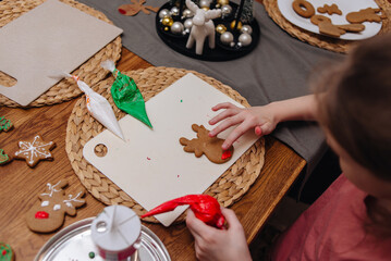 Happy funny little girl bake christmas cookies on cozy kitchen at home