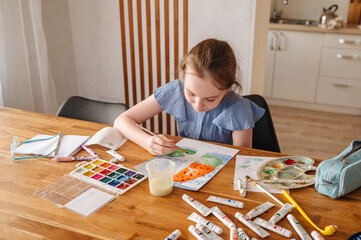 Cute little girl paints with paints