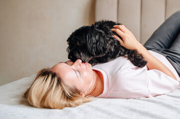 Woman relax on couch with puppy, happy and content at home with pet