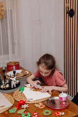 Happy funny little girl bake christmas cookies on cozy kitchen at home