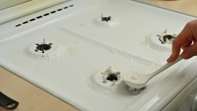 Person scrubbing white stove with brush