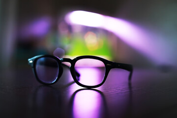 Stylish Glasses with Reflective Lenses on a Table in Moody Purple Lighting