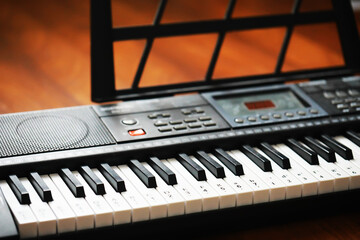 Electronic Keyboard on Wooden Surface with Music Stand in Warm Light