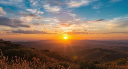 Golden sunset over hills with light flare and partly cloudy blue sky backdrop