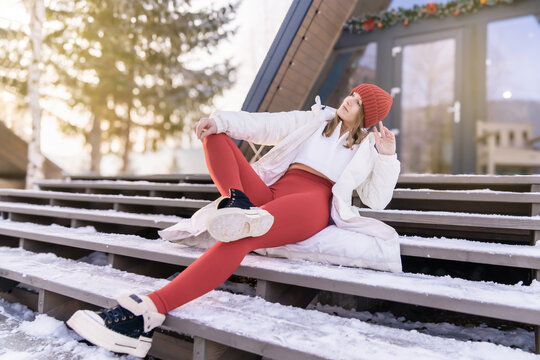 Young woman enjoying winter outdoors with stylish outfit on wooden stairs in a snowy landscape during sunrise - Powered by Adobe