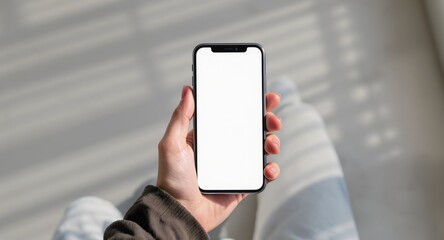 Person holding phone with blank white screen under window shadows