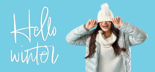 Happy woman in winter clothes on blue background. Hello winter
