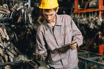Engineer technician male worker work in old used machine part stock warehouse.