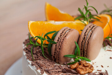 Delicious cake decorated with orange slices, macarons, and rosemary.