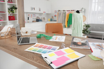Interior of stylish studio with laptop, color palettes and sketches on designer workplace