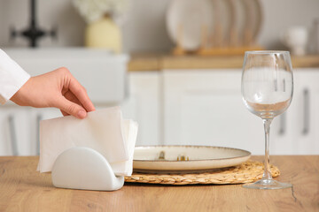 Woman taking paper napkin at table in kitchen