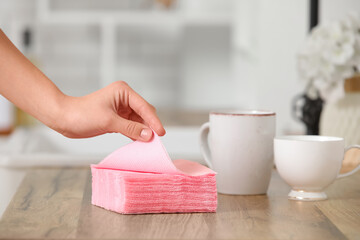 Woman with stack of pink paper napkins and cups at kitchen counter