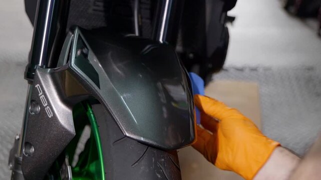 Applying ceramic coating to front mud guard fender on motorbike