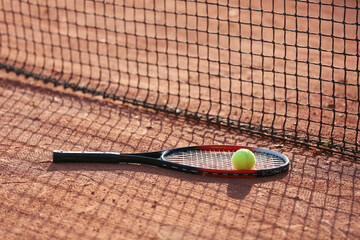 Racket with tennis ball near net on court floor