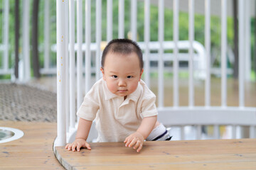 A young Asian boy practising crawling in an outdoor playground.