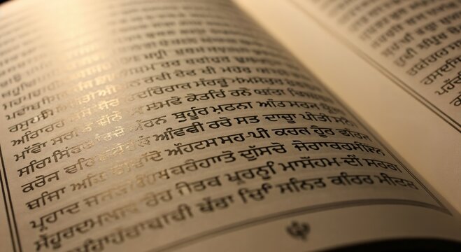 Close-up of an open sacred book, likely a Sikh scripture, displaying intricate Gurmukhi script on its pages, bathed in a warm, soft light, evoking spirituality and ancient wisdom.