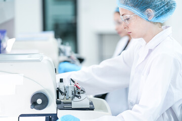 A histotechnologist carefully operates a microtome, precisely sectioning a paraffin embedded tissue block to prepare slides for pathological examination and cancer diagnosis.