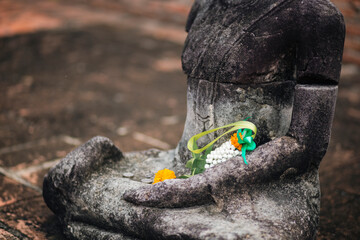 Floral patterns and coins religious offerings on a stone buddha sculpture in Ayutthaya, Thailand