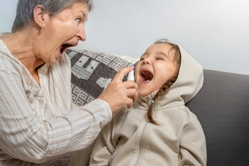 Senior woman spraying medicine into child's mouth