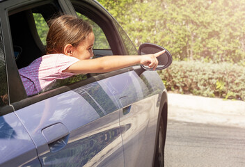 Child points finger out of car window