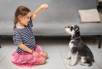 Child trains dog to sit on floor