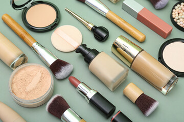 Composition with makeup brushes and cosmetic products on green background, closeup