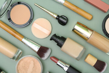 Composition with makeup brushes and cosmetic products on green background, closeup