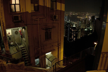 Derelict residential building on outskirts of business district at night time, high angle view. Back door of apartment with staircase in poor neighborhood, social contrast