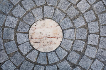 Motif circulaire en pavés de pierre grise et centre en marbre clair