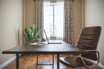 Fototapeta premium Empty Modern Home Office Workspace featuring Laptop, Desk, and Ergonomic Chair by a Bright Window. Perfect for Remote Work, Study, and Enhanced Productivity.