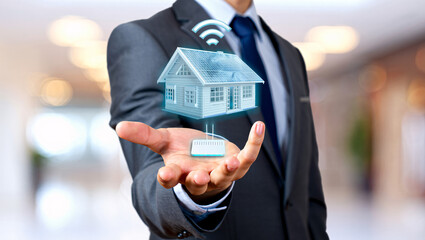 Businessman holding a holographic smart home with wireless connectivity in his hand
