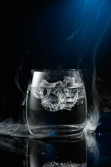 Vodka with ice on a black reflective background.