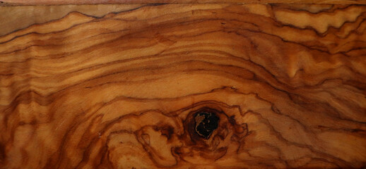 Wood texture background. Different shades of brown, ocher, orange, black. Natural curved lines and waves are unevenly arranged. Black spot at the bottom of the background. Floor, furniture, interior.