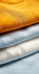 Stacked t-shirts in mustard yellow, light blue, and white