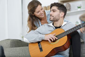 romantic couple are at home the man plays a guitar