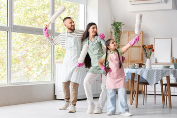 Naklejka premium Happy family with pp-dusters dancing while cleaning in kitchen