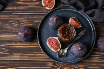 Tray with jar of sweet fig jam on brown wooden background, closeup