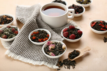 Bowls with different fruit tea and cup of brewed beverage on beige background
