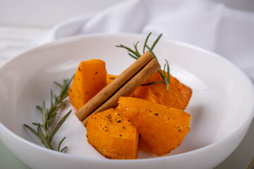 Baked pumpkin with thyme served on a plate as a unique dish on a white background.