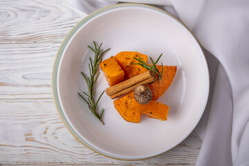 Baked pumpkin with thyme served on a plate as a unique dish on a white background.