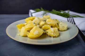 Boiled potatoes cut into pieces with dill. Ready dish on a gray background