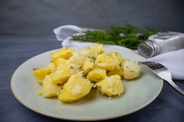 Boiled potatoes cut into pieces with dill. Ready dish on a gray background