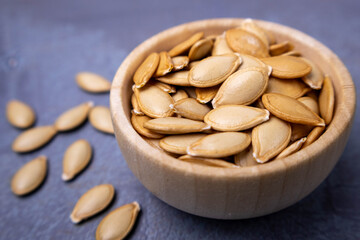 A bowl full of pumpkin seeds,on dark background